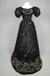 Evening gown, Marie Lamy of Paris, black silk satin with a black-sequined overlay and short puffed sleeves, 1890s, back view