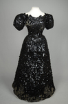 Evening gown, Marie Lamy of Paris, black silk satin with a black-sequined overlay and short puffed sleeves, 1890s, front view