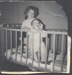 Two young children, Holly and Jimmy, standing in crib by Unknown