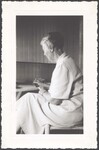 Unidentified woman sitting at a desk writing