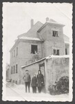 A German family standing outside in the snow near stone wall and building by Cobb, Ivorey, 1911-1992