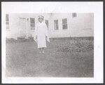 Gretel Anne Cobb in graduation cap and gown standing in yard by Unknown