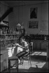 Assistant of Ivan Michurin, smiling and working at a lab bench in Michurinsk, Russia, USSR, ca. 1932-1933 by Jacobi, Lotte, 1896-1990